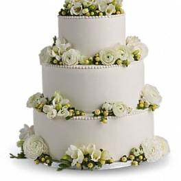 Four-tier white wedding cake with white floral decorations