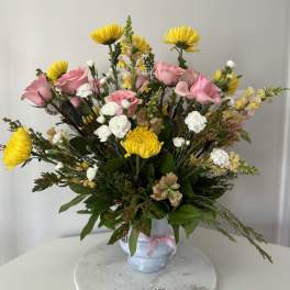 Pink roses and yellow chrysanthemums arranged in a white vase