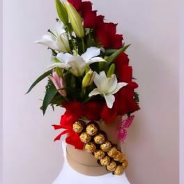 Red and white lily arrangement with gold chocolates on a hat box