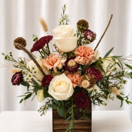 Cream roses and burgundy blooms arranged in a wooden box