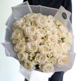 Bouquet of cream white roses wrapped in pale paper