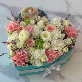 Heart-shaped box of pink and white flowers with a ribbon