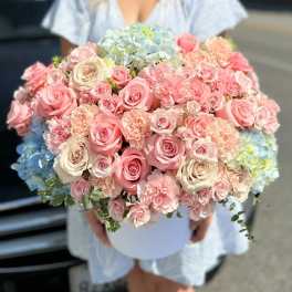 Large bouquet of pink and cream roses with blue hydrangeas in a white box