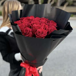 Bouquet of red roses wrapped in black paper with a red ribbon