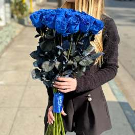 Woman holding a large bouquet of vivid blue roses