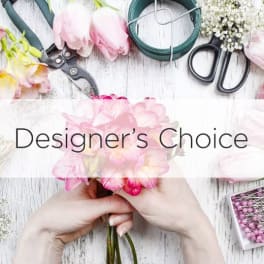 Hands holding pink flowers beside floral tools and supplies