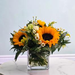 Sunflower bouquet with white daisies in a clear glass vase