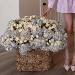 Large basket arrangement of cream roses and pale blue hydrangeas