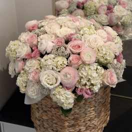 Large pink and white rose arrangement in a woven basket