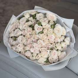 Bouquet of pale pink and white roses wrapped in white paper
