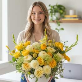 Woman holding a large yellow and white flower arrangement in a white pedestal vase