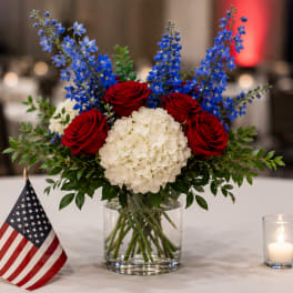 Red roses and white hydrangea in a glass vase with blue flowers