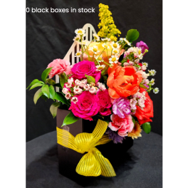 Colorful mixed flower arrangement in a black box with a yellow ribbon