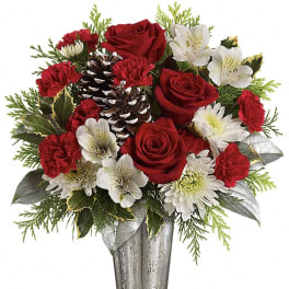 Tall silver vase with red roses, red carnations, white alstroemeria and mums, evergreens, and pinecones