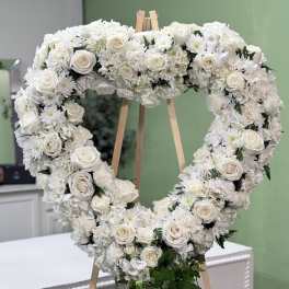 White floral heart wreath on a wooden easel with trailing ivy