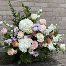Pastel bouquet with roses, hydrangeas, and daisies against a brick wall