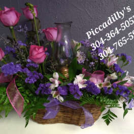 Basket arrangement of pink roses and purple flowers with a glass lamp chimney