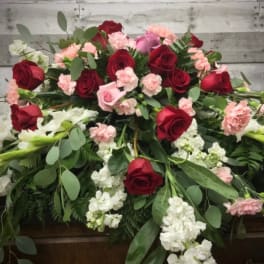 Casket spray with red roses, pink carnations, and white flowers