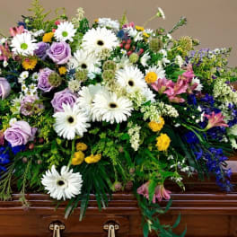 Large casket spray with white daisies, lavender roses, and mixed blooms