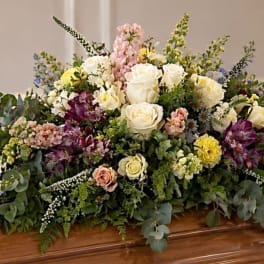 Large casket spray with white, pink, yellow, and purple flowers