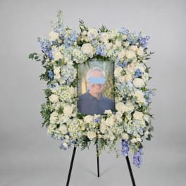 Large floral easel spray framing a portrait with white and blue flowers