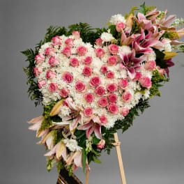 Heart-shaped floral spray with pink roses and lilies on an easel