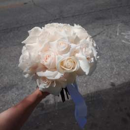 White rose bouquet with a blue ribbon tied around the stems