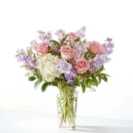 Pink roses and lavender flowers in a clear glass vase