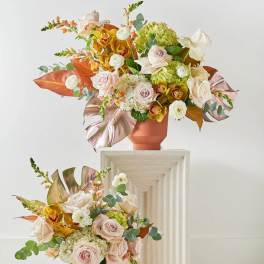 Two pastel floral arrangements in terracotta vases on pedestals