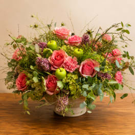 Pink roses and green hydrangeas in a low ceramic bowl with green apples