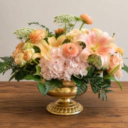 Peach and blush floral arrangement in a gold pedestal vase
