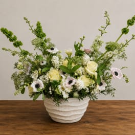 White and pale yellow floral arrangement in a textured ceramic vase