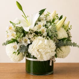 White floral arrangement in a glass vase with lilies and hydrangeas