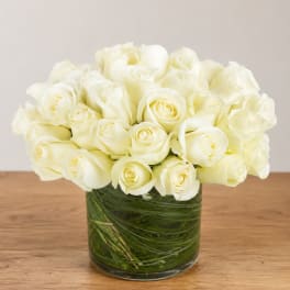 White roses arranged in a clear glass vase with green stems visible
