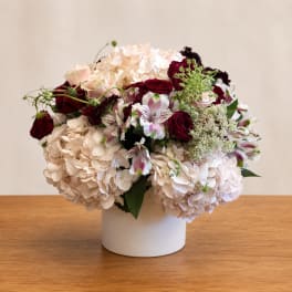 Bouquet of cream hydrangeas, red roses, and white alstroemeria in a white vase