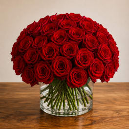 Red roses arranged in a clear glass vase on a wooden table