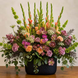 Large mixed floral arrangement in a black woven container