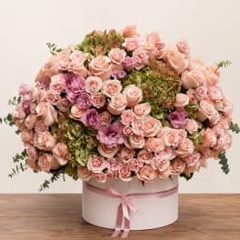 Large pink and peach rose arrangement in a round box with ribbon