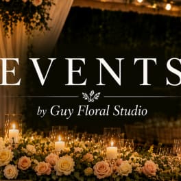 Low floral table arrangement with blush and ivory roses around candles and glassware