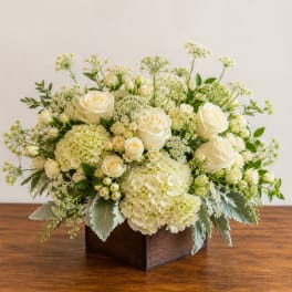 Cream roses and hydrangeas arranged in a wooden box
