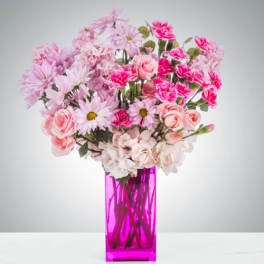 Pink mixed flowers arranged in a tall magenta vase