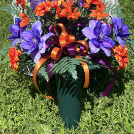 Colorful bouquet of purple and orange flowers in a green vase with ribbon