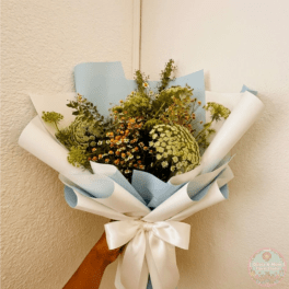Handheld bouquet of white and green flowers wrapped in blue and white paper