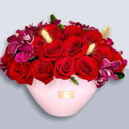 Red roses and purple orchids in a pink heart-shaped box