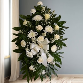 White floral standing spray with roses and chrysanthemums on dark greenery