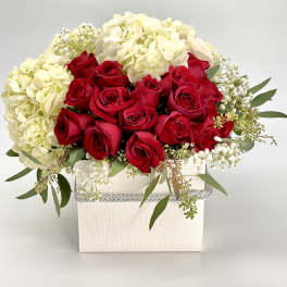 Box arrangement of red roses and white hydrangeas in a white square container