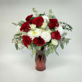 Arrangement of red roses and white chrysanthemums in a red glass vase