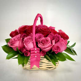 Basket of red and pink roses with a wrapped handle and ribbon accents