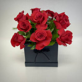 Compact arrangement of red roses in a black rectangular box container