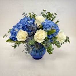 Blue hydrangeas and white roses arranged in a blue vase